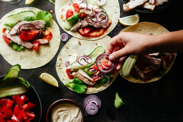 Tortillas di mais ripiene di pollo e verdure su un tavolo di legno Cottura dei tacos