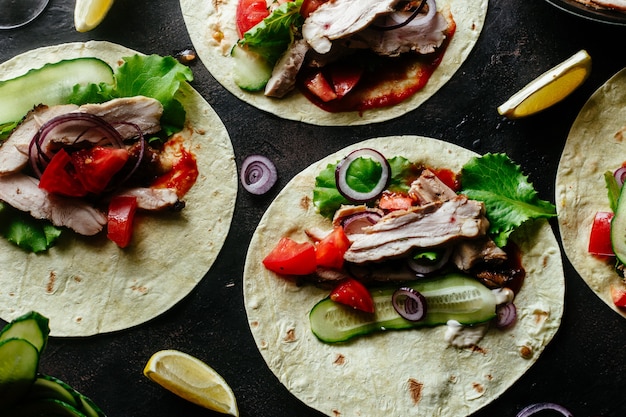 Tortillas di mais ripiene di pollo e verdure su un tavolo di legno Cottura dei tacos