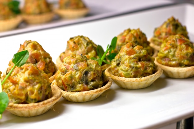 Tortine con verdure al forno ed erbe aromatiche su una porcellana bianca di