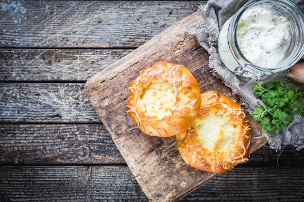 Tortini aperti fatti in casa freschi con formaggio. Pasta lievitata tradizionale russa, panini rotondi, crostata di cagliata. Panini con ricotta. Stile rustico. Fondo in legno, vista dall'alto