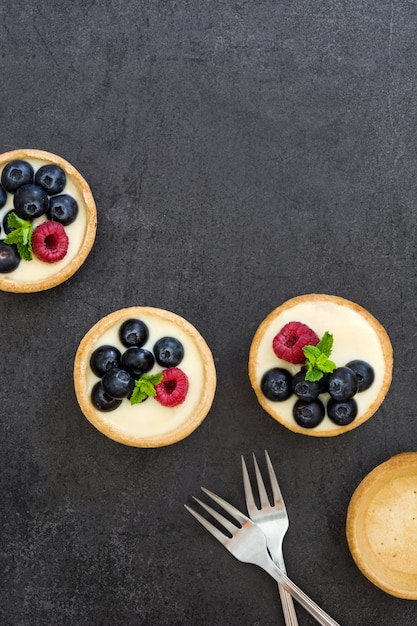 Tortini deliziosi con i lamponi e i mirtilli sul nero