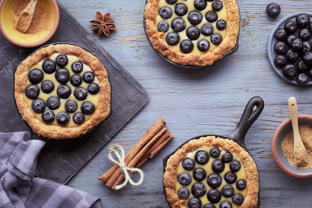 Tortini deliziosi del mirtillo con crema pasticcera alla vaniglia su di legno