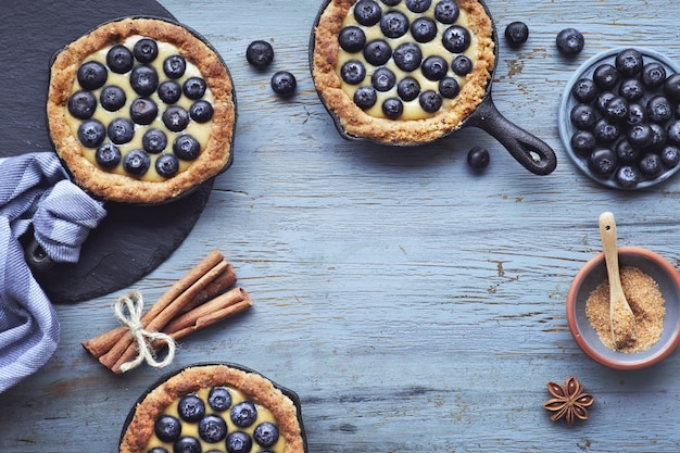 Tortini deliziosi del mirtillo con crema pasticcera alla vaniglia su legno rustico leggero