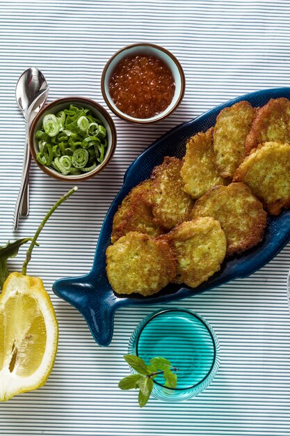 Tortini di pesce serviti sul tavolo con caviale rosso, cipolle verdi e panna acida. piatto di pesce fatto in casa