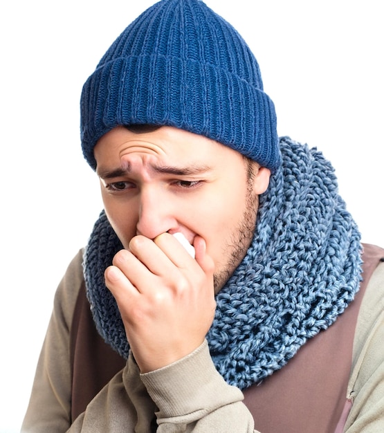 Tosse giovane uomo malato che indossa cappello invernale con sciarpa che mette la mano sulla bocca isolata