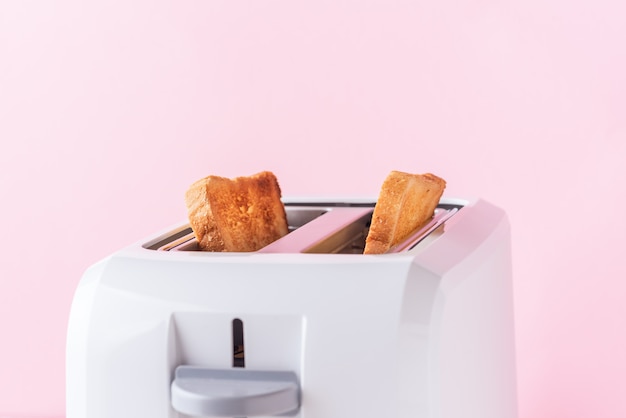 Tostapane bianco con pane arrosto su sfondo rosa