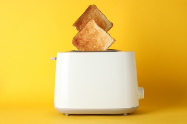 Tostapane con fette di pane su sfondo giallo, spazio per il testo