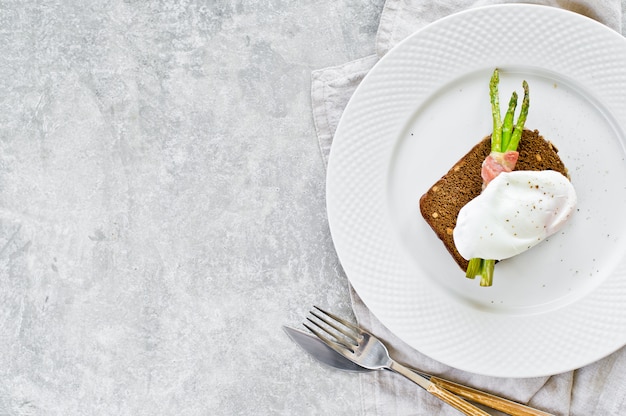 Tostare con uovo in camicia e mini asparagi grigliati al bacon.