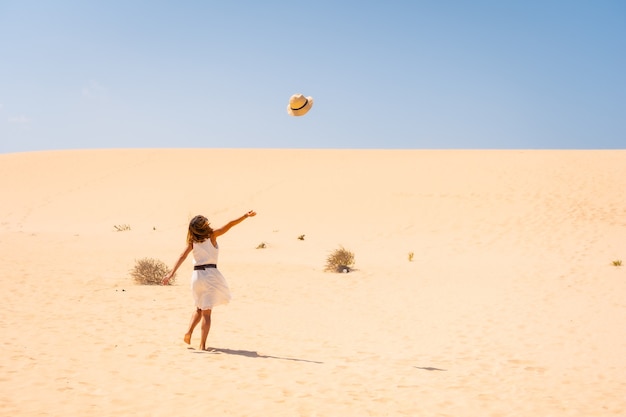 Tourist lanciando i suoi cappelli molto felice tra le dune del Parco Naturale di Corralejo, Fuerteventura, Isole Canarie. Spagna