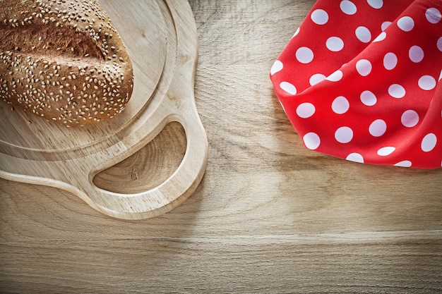 Tovaglia a pois rossa del tagliere di intaglio del pane su fondo di legno