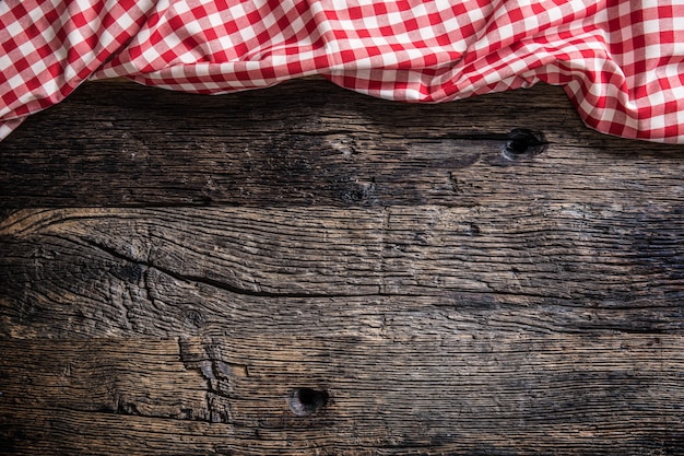 Tovaglia a quadretti rossa della cucina sulla tavola di legno rustica.