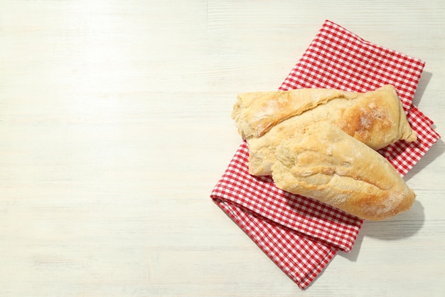 Tovaglia a quadretti rossa e bianca con pane su fondo di legno bianco