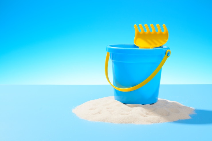 Photo toy plastic pail and a rake on the sand