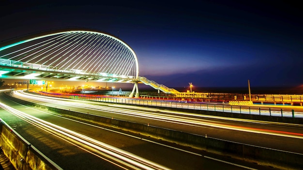 Tracce di luce sulla strada sul ponte contro il cielo di notte