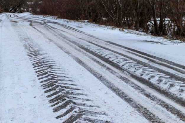 Tracce di pneumatici su strada ghiacciata ricoperta di neve