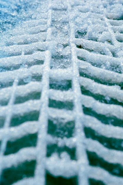 Tracce verticali di pneumatici per auto nella neve sull&#39;asfalto.