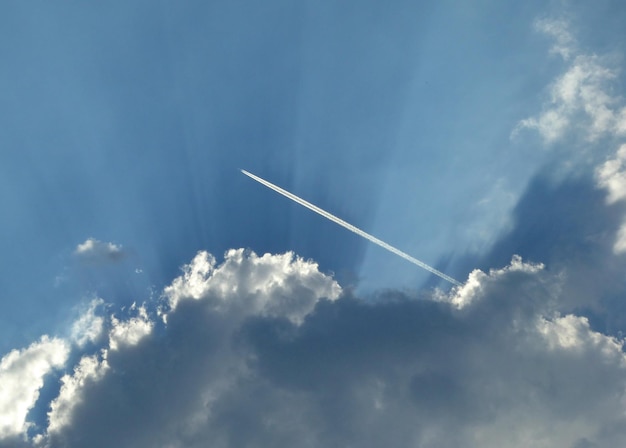 Traccia dell'aeroplano sul cielo nuvoloso blu