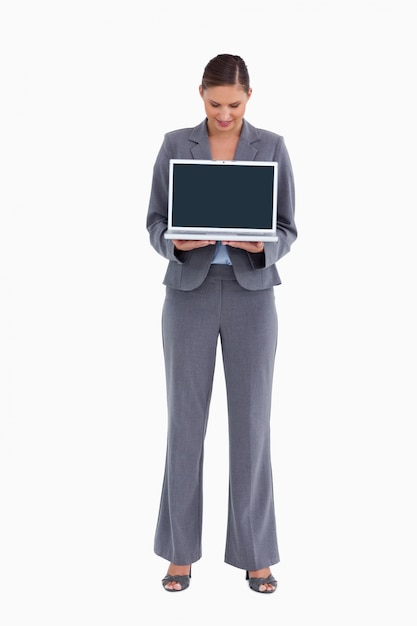Tradeswoman che presenta e guardando lo schermo del laptop
