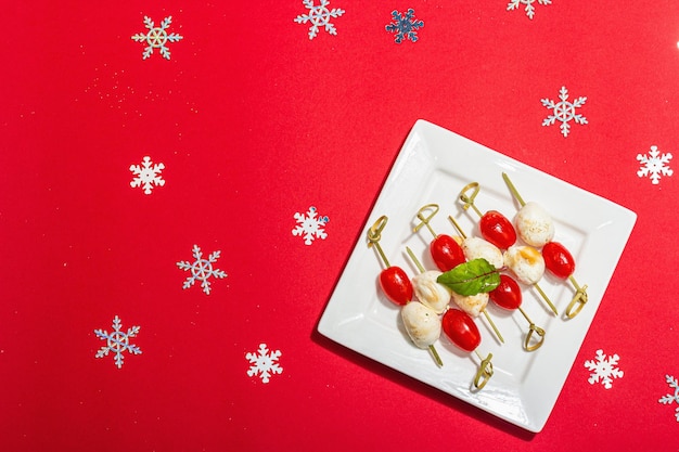 Tradizionale aperitivo italiano in stile natalizio Mozzarella pomodori di ciliegio su spiccioli Anno nuovo