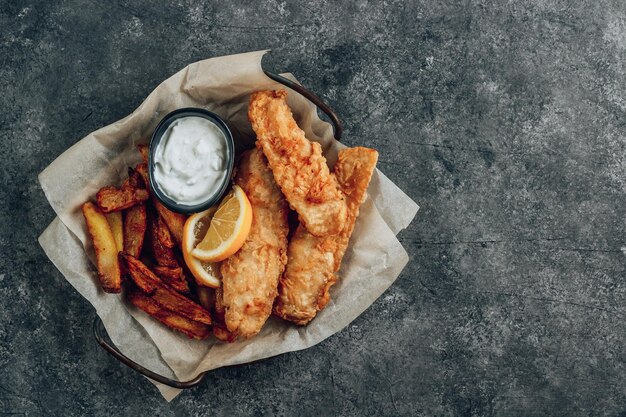 Tradizionale British Fish and Chips con salsa tartara su sfondo di cemento