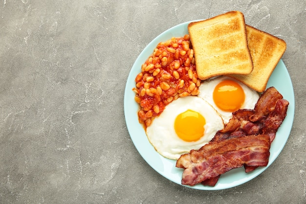 Tradizionale colazione inglese completa con uova fritte, fagioli, pancetta e pane tostato
