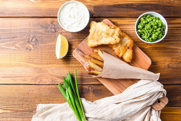 Tradizionale Fish and chips con purè di piselli salsa tartara inn carta stropicciata cono