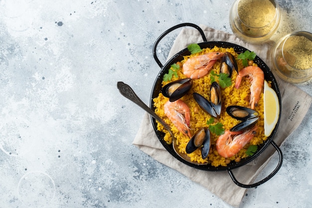 tradizionale paella spagnola di pesce in padella su elegante sfondo di marmo chiaro, vista dall'alto