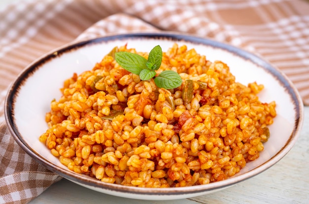 Tradizionale pilaf bulgur turco con salsa di pomodoro in piatto nome turco meyhane pilavi