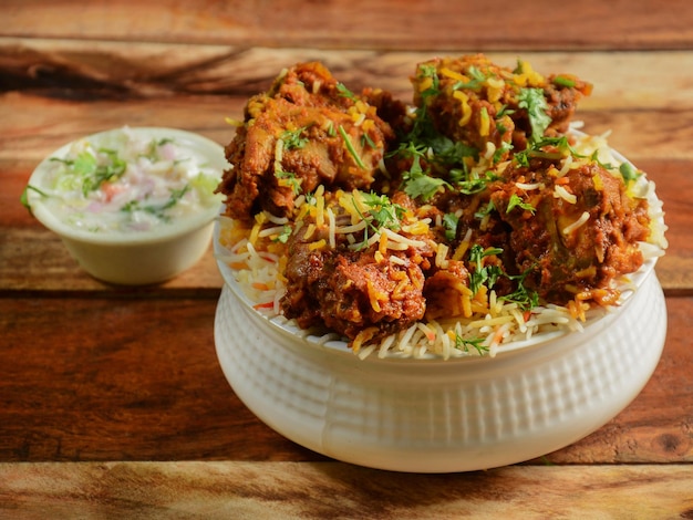 Tradizionale pollo Hyderabadi dum Biryani a base di riso Basmati cotto con spezie masala servito con cipolla raita fuoco selettivo