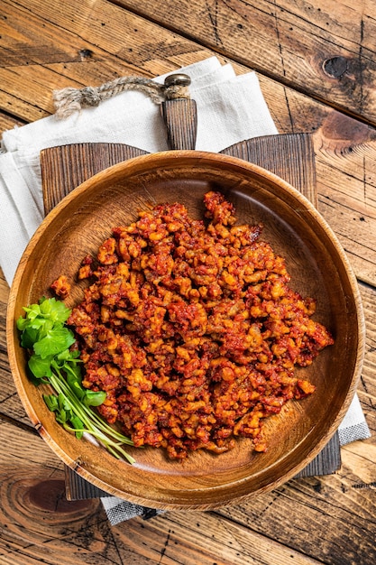 Tradizionale salsa di pomodoro alla bolognese con carne macinata in un piatto di legno con erbe aromatiche Sfondo in legno Vista dall'alto