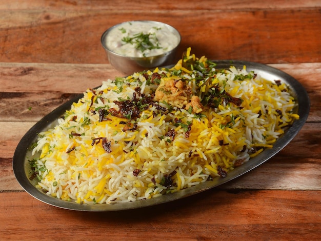 Tradizionale verdura hyderabadi dum biryani con verdure miste servita con fuoco selettivo raita misto