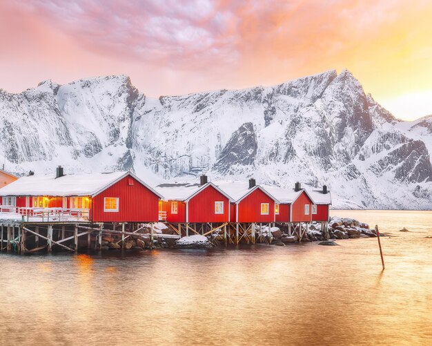 Tradizionali case di legno rosso norvegesi rorbuer sulla riva del Reinefjorden vicino al villaggio di Hamnoy al tramonto