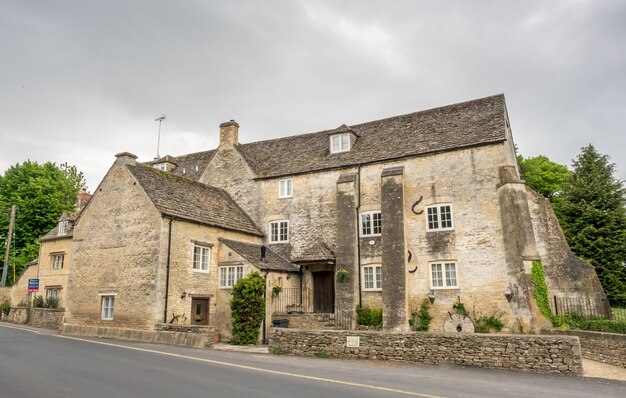 Tradizionali cottage in pietra nel tranquillo villaggio di Bibury, in Inghilterra, nel Cotswold, sotto il cielo nuvoloso