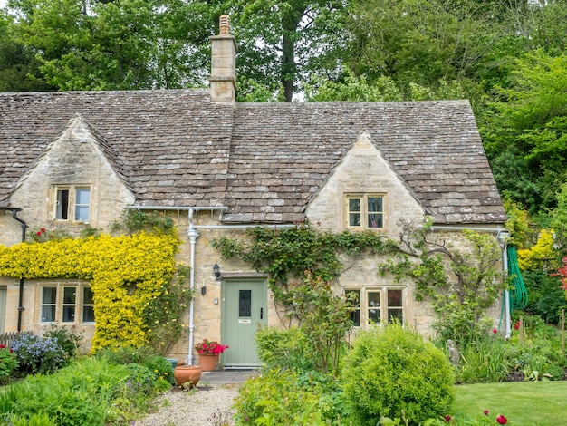 Tradizionali cottage in pietra nel tranquillo villaggio di Bibury, in Inghilterra, nel Cotswold, sotto il cielo nuvoloso