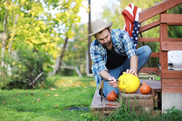 Tradizioni autunnali e preparativi per la festa di Halloween. Una casa nella natura, una lampada fatta di zucche si ritaglia a tavola.