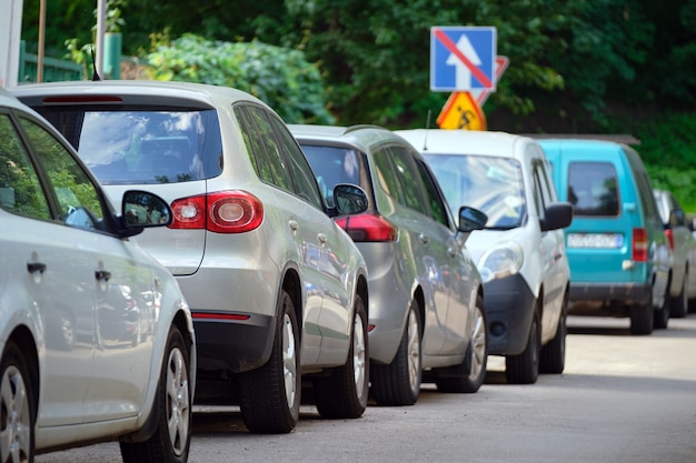 Traffico cittadino con auto parcheggiate in fila sul lato strada.