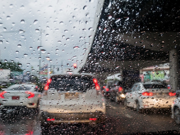 Traffico in una giornata di pioggia con vista sulla strada attraverso il finestrino dell'auto con gocce di pioggia