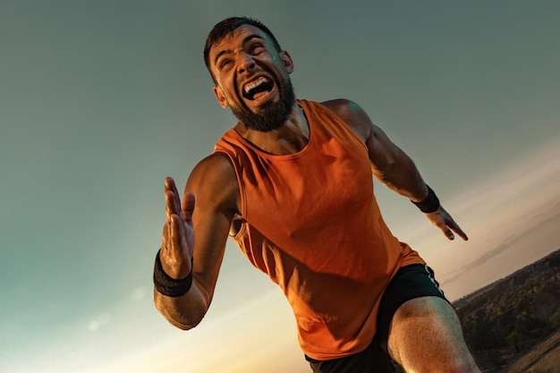 Trail runner concetto atleta sprinter corsa uomo atletico forte che corre al tramonto sullo sfondo che indossa