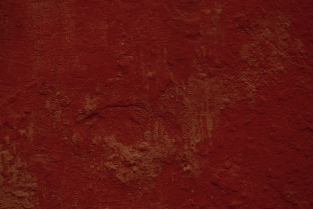 Trama di sfondo rosso scuro di una parete dipinta con superficie ruvida e macchie