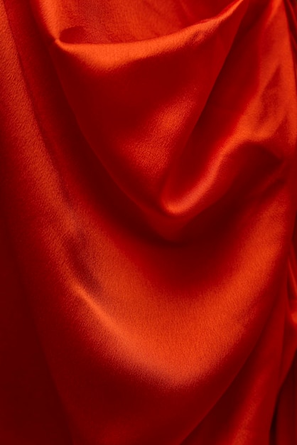 Trama ondulata di tessuto di raso rosso closeup Materiale di seta o raso Sfondo tessile Cornice verticale di stoffa luminosa