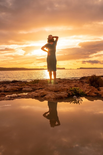 Tramonto a Ibiza in vacanza una giovane donna in riva al mare a San Antonio Abad Baleari