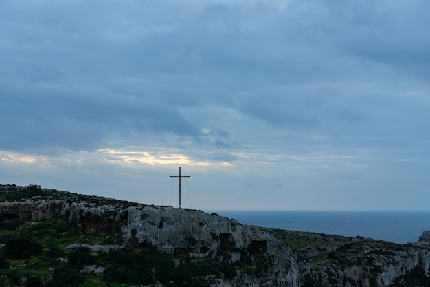 Tramonto a Mellieha con il fondo del mare e una croce in lontananza