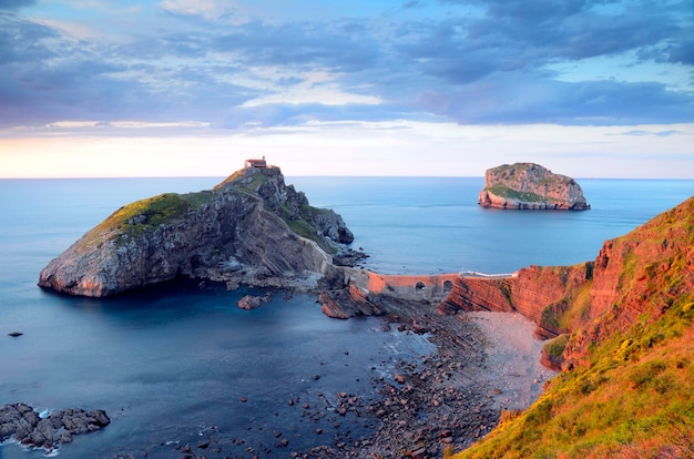 Tramonto a San Juan de Gaztelugatxe con l'isola di Aketx sullo sfondo e un mare calmo