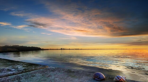 tramonto arancio dorato drammatico cielo nuvoloso di notte e riflesso dell'onda dell'acqua di mare