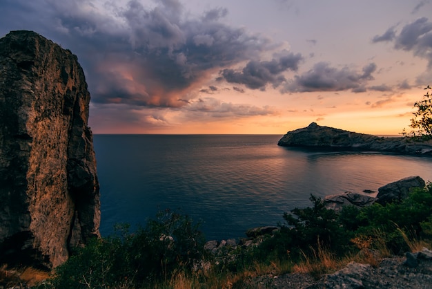 tramonto arancione rosso contro l'azzurro del mare e delle montagne