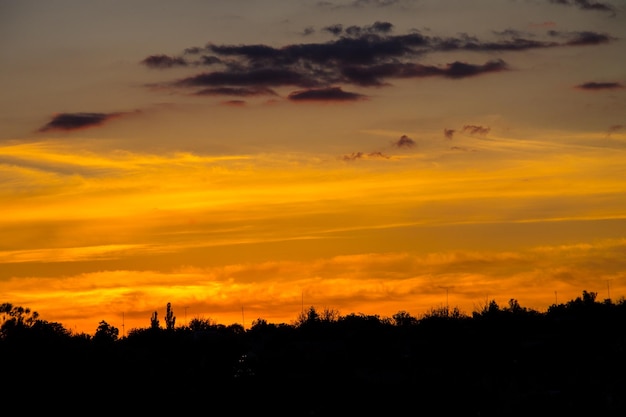 Tramonto arancione sopra le sagome del villaggio e degli alberi