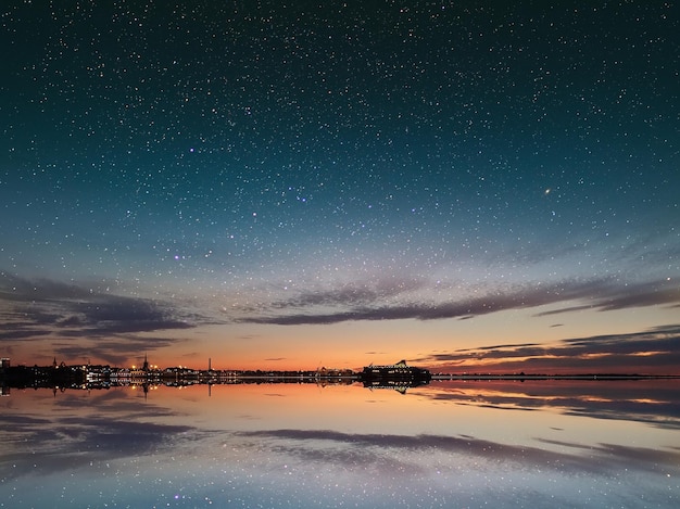 tramonto arancione sul cielo stellato blu di notte riflesso della luna sull'onda d'acqua