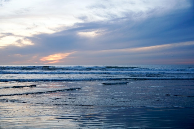 Tramonto arancione variopinto della spiaggia dell'oceano con il cielo velato profondo. Bella nuvola sopra il mare durante il tramonto