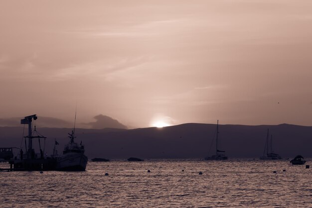 Tramonto che si riflette sul mare Barche nella spiaggia di Paracas Perù