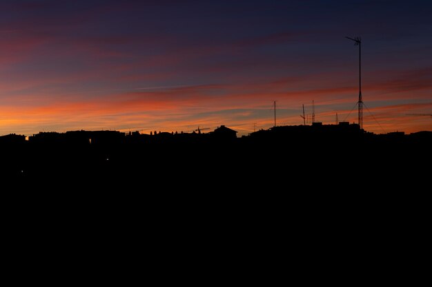 Tramonto colorato cielo con sagome di case Cielo colorato durante il tramonto con silhouette di case Bel cielo colorato con case in controluce